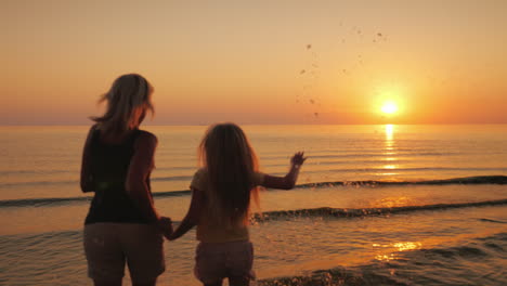 Mama-Und-Tochter-Gehen-Auf-Dem-Wasser-Vor-Dem-Hintergrund-Der-Untergehenden-Sonne