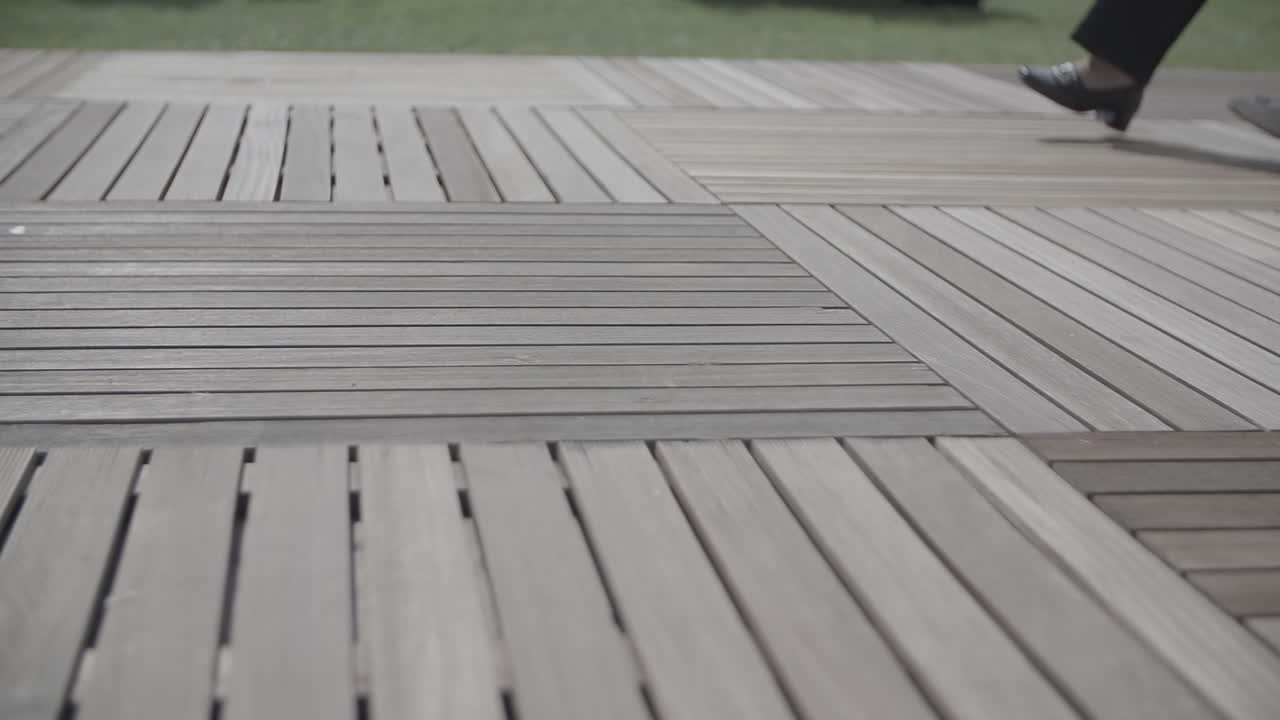 Nærbillede af flere personer, der går ved siden af hinanden på et trægulv i slowmotion LOG