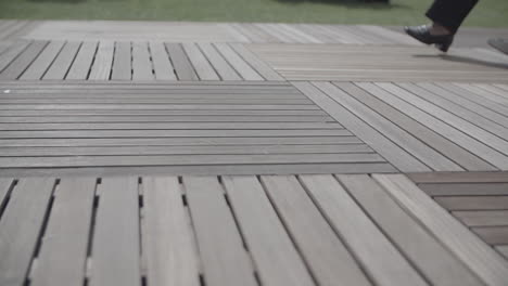 Close-up-shot-of-multiple-people-walking-next-to-each-other-on-a-wooden-floor-in-slowmotion-LOG