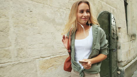 close-up view of caucasian blonde young woman walking down the street while jumping and listening to music