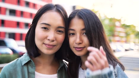 openluchtportret van twee mooie jonge japanse meisjes die naar de camera kijken en glimlachen