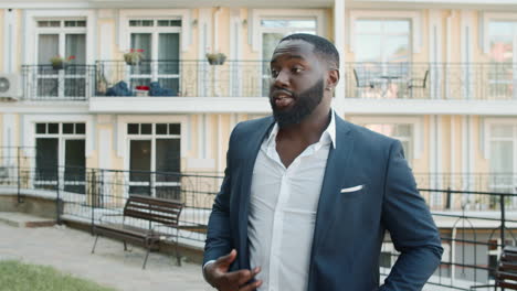 joyful african businessman dancing outdoors. happy business guy having fun