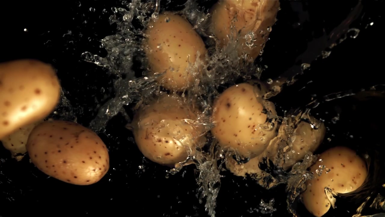 Patate fresche che cadono e schizzano nell'acqua al rallentatore