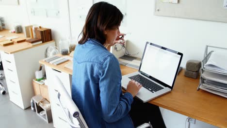 Female-executive-sitting-at-desk-and-using-laptop