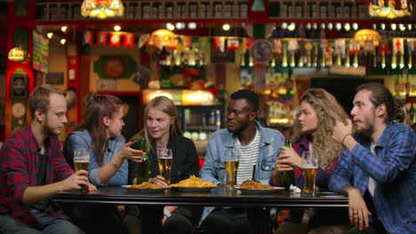 afroamericano con amigos en un bar bebiendo cerveza y comiendo papas fritas con amigos.