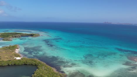 aerial right pan of a stunning turquoise lagoon and lush mangrove forest