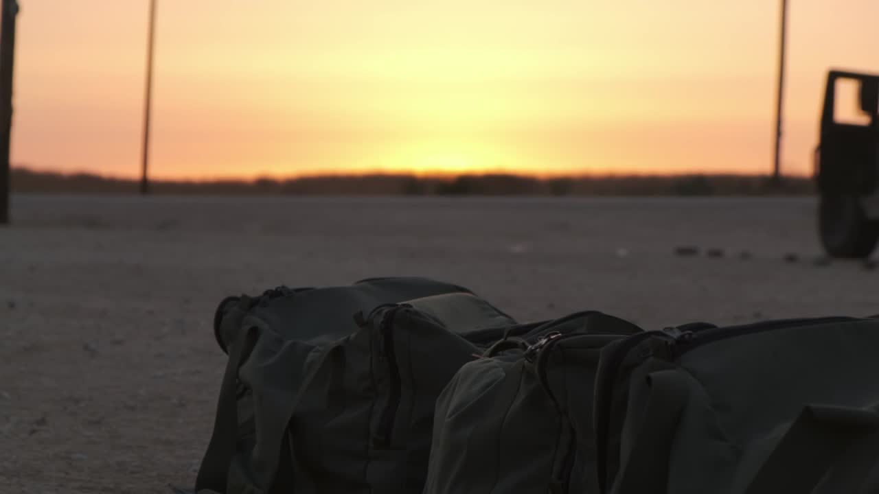 Military army bugs in the middle of the desert while in the background there is a military Vehicle during the amazing orange sunset next to a field