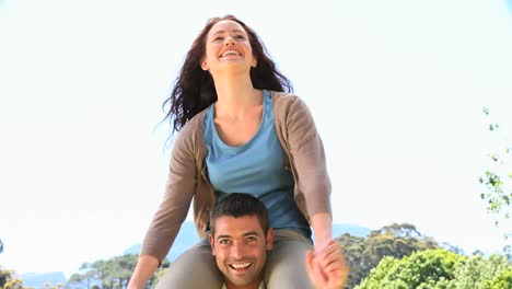 smiling woman on the shoulders of her husband