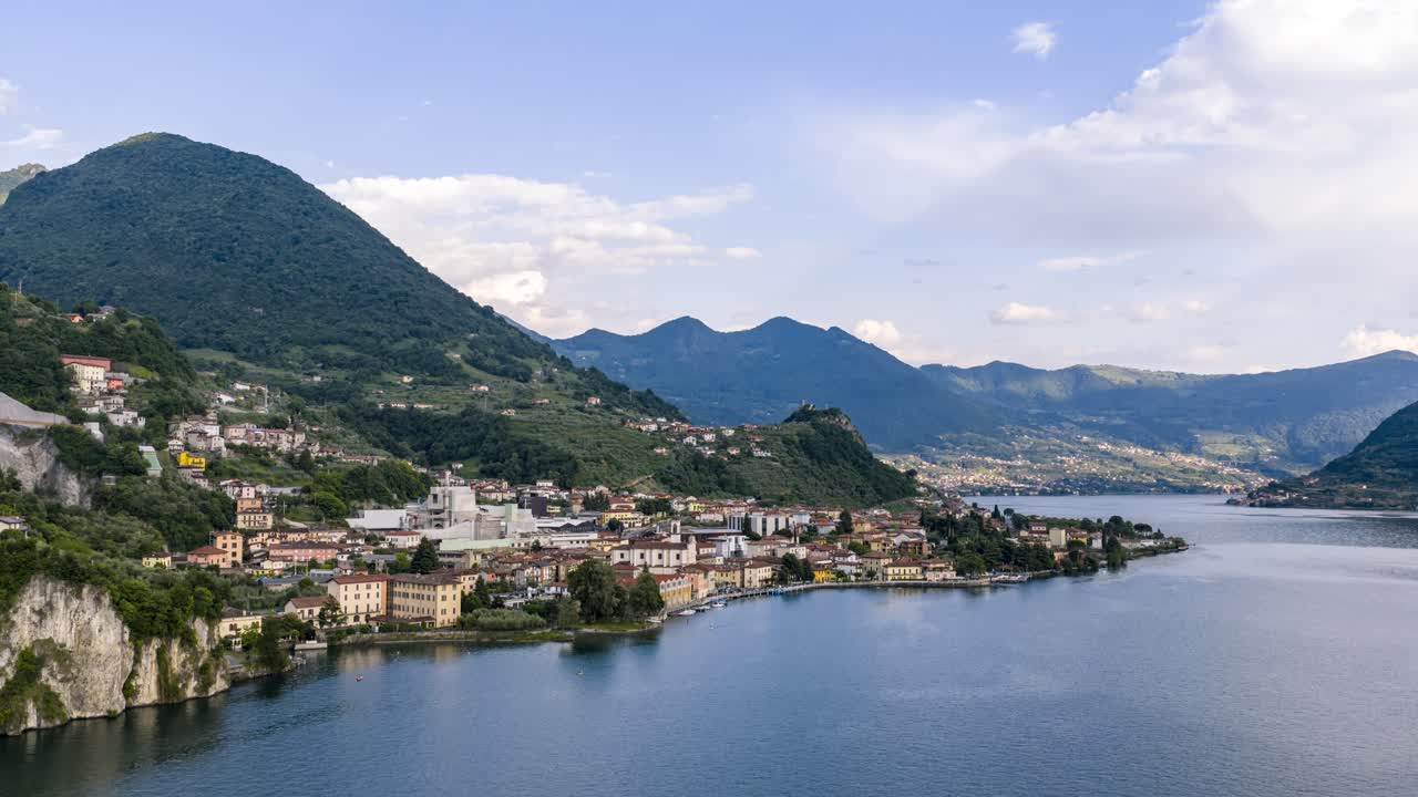 Veduta aerea in hyperlapse di Marone, Italia, che mostra edifici sul lago, scogliere, montagne ondulate e acqua serena