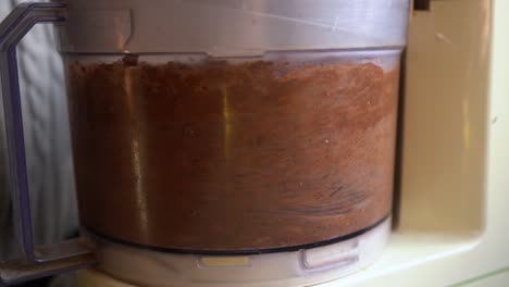 close up of food processor blending raw ingredients for baking cookies