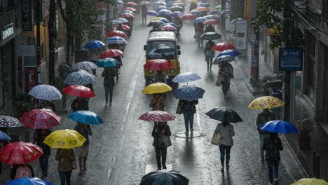 people with colorful umbrellas walk on a wet city street in the rain