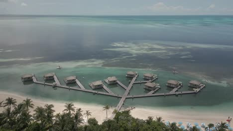 Flyover-small-tourism-cabanas-on-Coco-Cay,-tiny-Bahamas-coral-islet