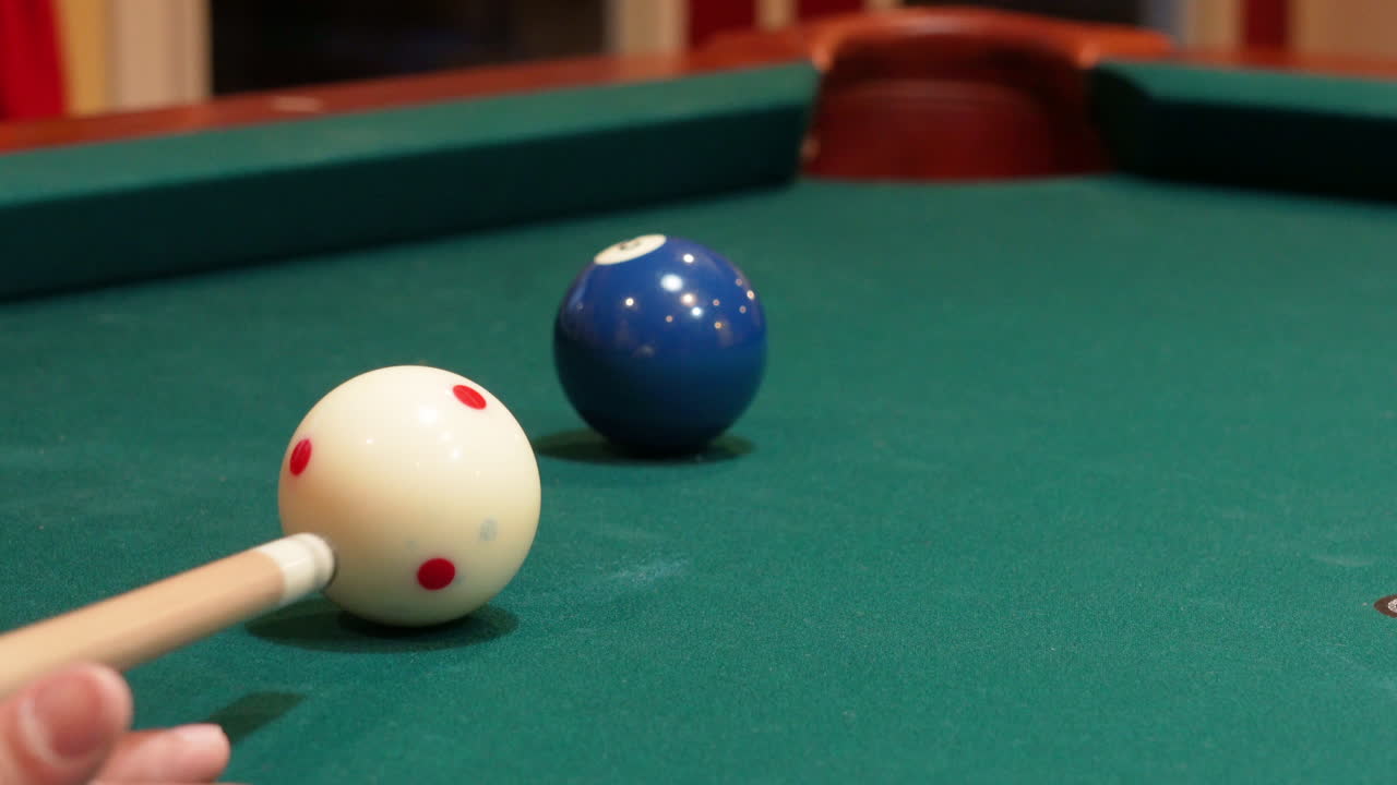 Closeup of Person Playing Pool Shooting Solid Blue 2 Ball into Corner Pocket after Practice Strokes using Cue Ball with Red Spots, Open Bridge Hand with Wooden Cue Stick and Green Felt or Cloth