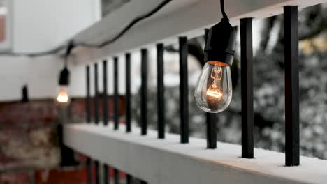 primer plano de las modernas luces de las bombillas que decoran al aire libre en la terraza durante el día de nieve en invierno