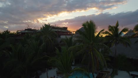 Aerial-view-of-a-tourist-complex-among-palm-trees-in-a-beautiful-sunset