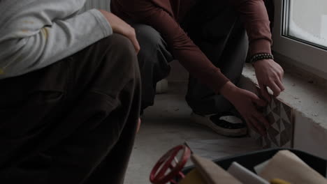 two people installing floor tiles during home renovation