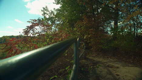 Slow-dolly-down-metal-hand-rail-on-a-forest-path