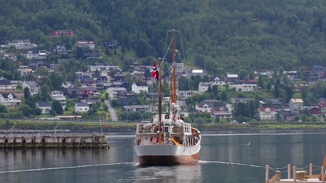 Vessel Hermes II approaching the harbour in Tromsø, Norway. The scene captures calm fjord waters, scenic Nordic architecture, and traditional maritime heritage, slow motion