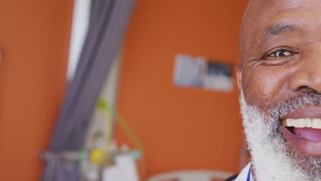 retrato de video de medio rostro de un feliz médico afroamericano sonriendo en el hospital, con espacio para copiar