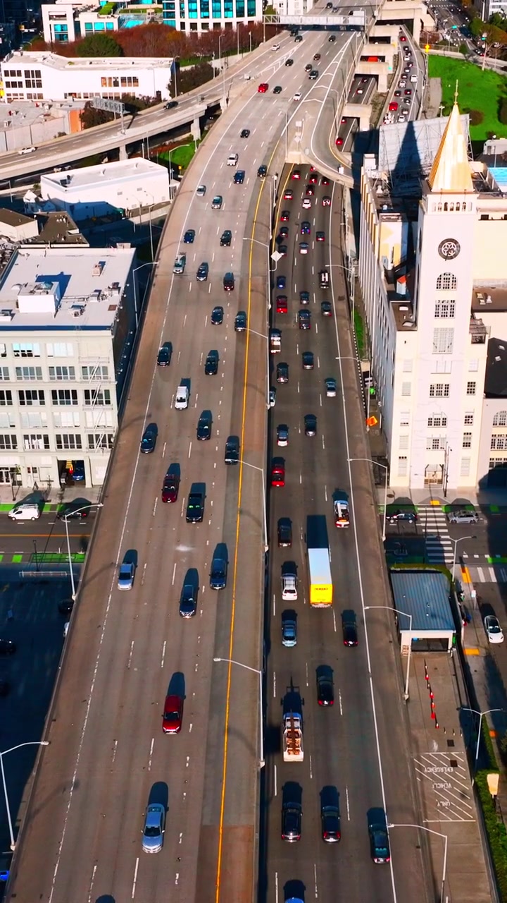 Vista dall'alto di un'autostrada sopraelevata con traffico, San Francisco. Ripresa con drone diurna che mostra diverse corsie di auto accanto a edifici e un parco verde. Video verticale