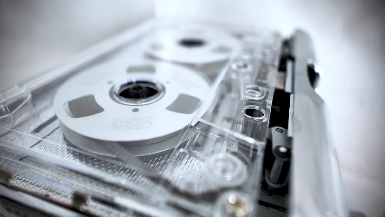 Nostalgi og retro lydteknologi: et klart kassettebånd med spoler der snurrer. Vintage musik.