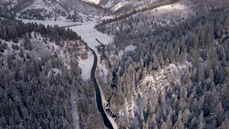 vehicles traveling across road with mountain ranges at background during winter at american fork canyon in wasatch mountains, utah, usa