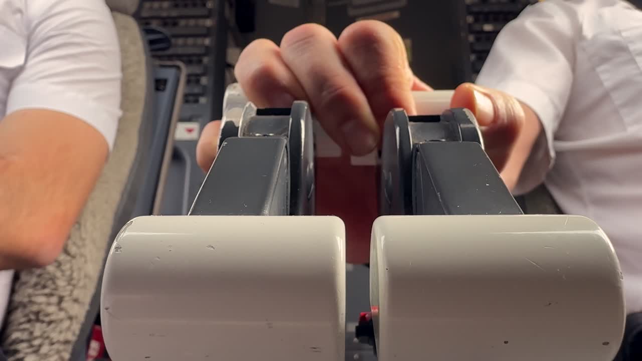 Close-up view of the hands of a pilot adjusting the thrust levers in a real time flight. Low angle shot