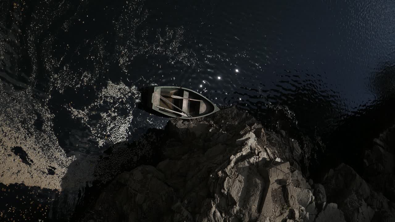 물 위 에 떠 있는 작은 나무 시 보트, 로프 로 바위 에 고정 되어 있다