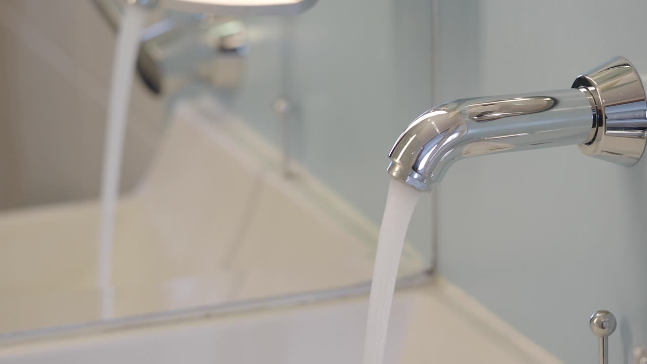 Acqua che scorre da un rubinetto cromato nella vasca da bagno.