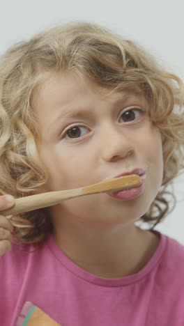 una niña pequeña cepillándose los dientes en vertical