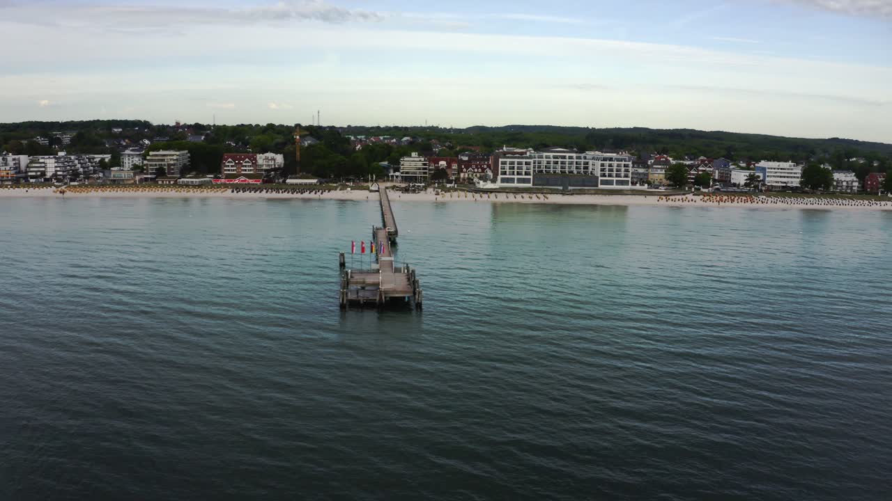 독일 슐레스비히홀슈타인(scharbeutz)에 있는 샤르보이츠(scharbeutz) 부두의 전망은 마을의 해변과 해안가 건물을 바라보는 물에서 볼 수 있습니다.