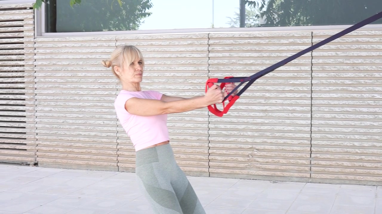Woman in pink top does outdoor resistance band workout for cardio endurance and strength