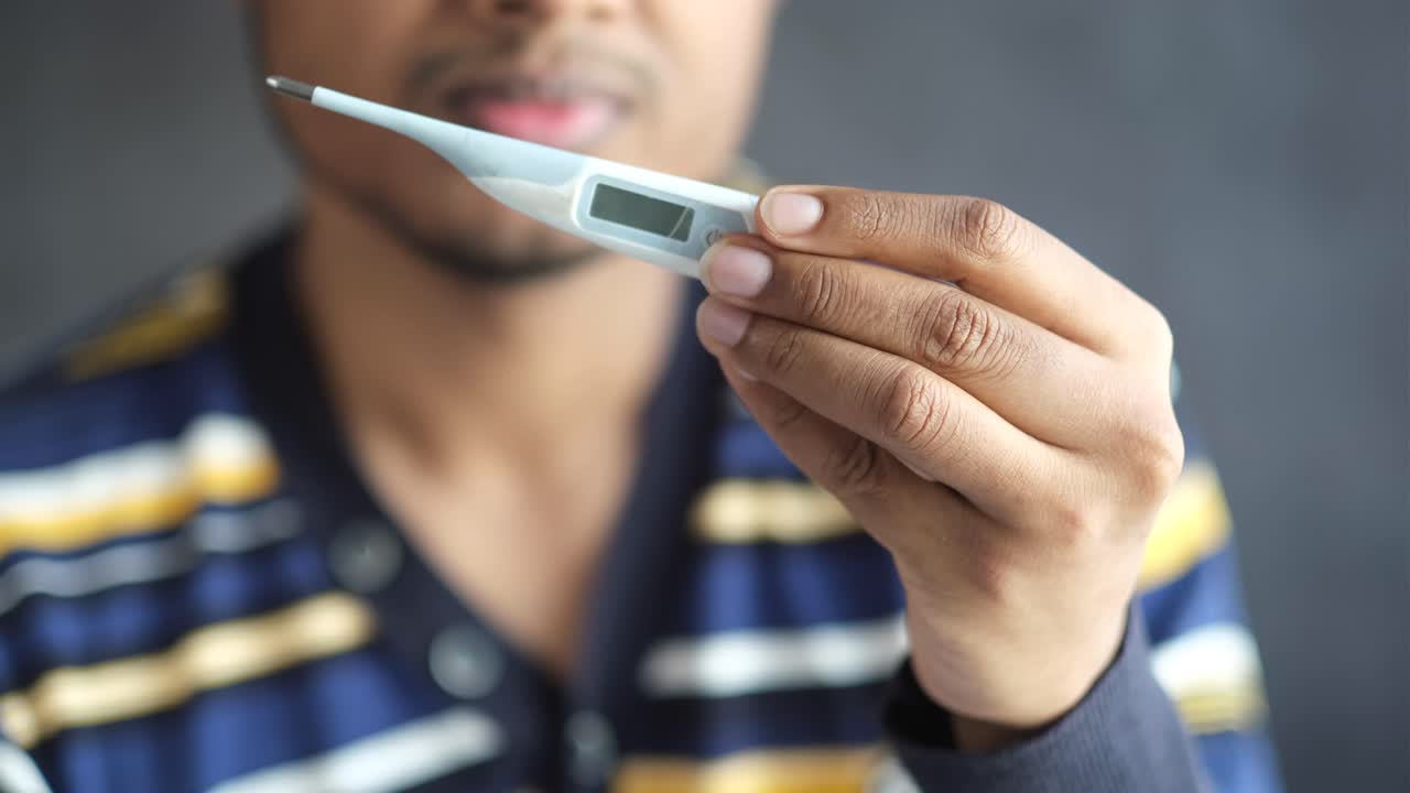 디지털 온도계로 체온을 확인하는 사람