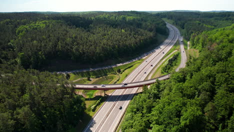 Hermosa-Vista-Aérea-De-La-Intersección-Del-Puente-Y-El-Tráfico-De-La-Carretera-En-La-Zona-Rural-Del-Bosque-Verde