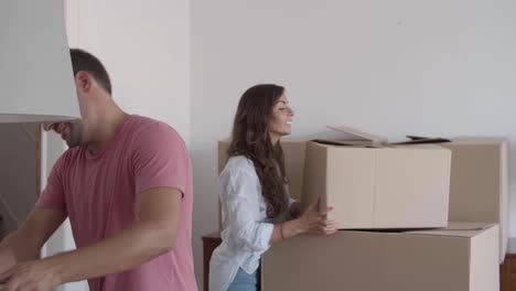 happy man giving cardboard boxes to girlfriend who putting them on each other