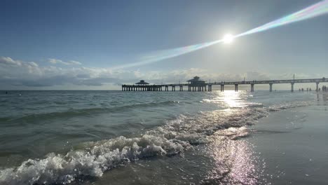 waves rolling at fort myers beach pier, sun on a clearday at the beach