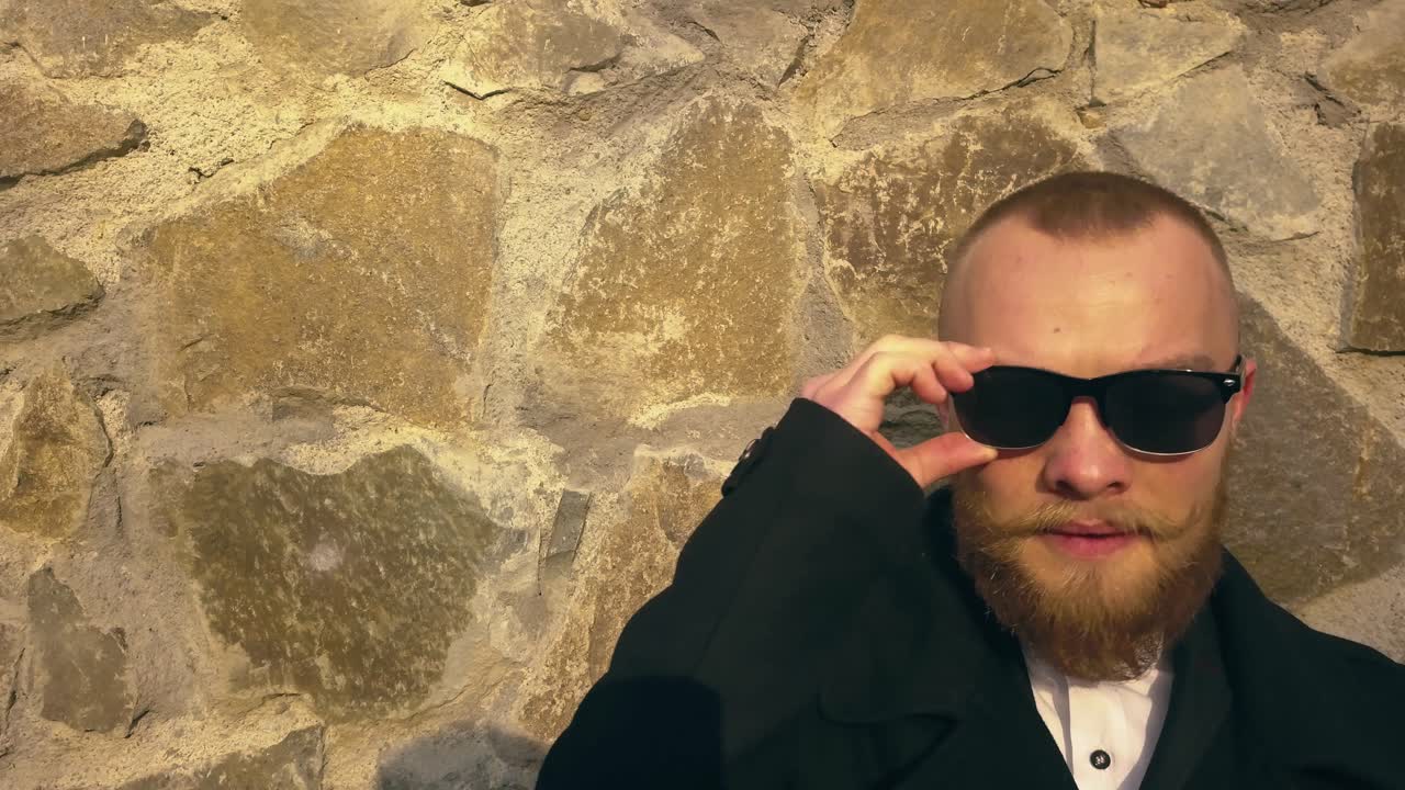 таинственный человек, стоящий у булыжной стены и наблюдающий за кем-то или чем-то