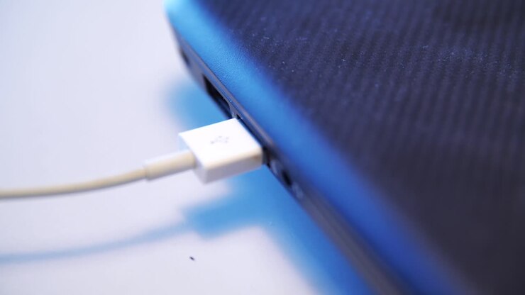 Hand connecting USB cable to laptop