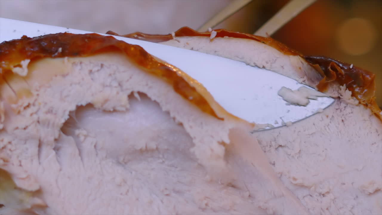 Câmera lenta de um delicioso peru assado sendo cortado com uma faca afiada, mostrando a pele crocante. Ave assada tradicionalmente consumida no Dia de Ação de Graças. Ideal para vídeos sobre culinária natalina caseira.