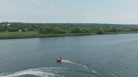 paralaje alrededor de un jet ski arrastrando una tableta con dos pasajeros muy rápido movimiento pasajeros apenas aguantando