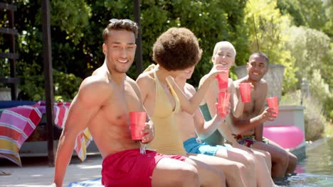 porträt von glücklichen, vielfältigen freunden, die im sommer an einer poolparty trinken