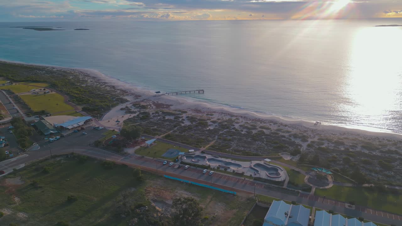 Cinematic aerial footage of Jurien Bay at Sunset in Perth, Western Australia. The footage pans horizontally to show the beach, the jetty and the town