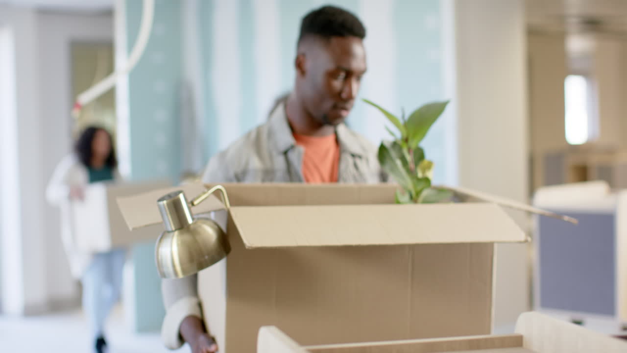 Casual diverse businesspeople carrying boxes moving into office, slow motion with copy space