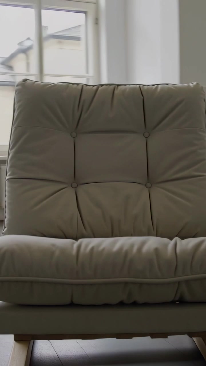 Video vertical: Cámara panorámica mostrando una silla capitoné de color beige en una habitación, revelando el acolchado y la base de madera