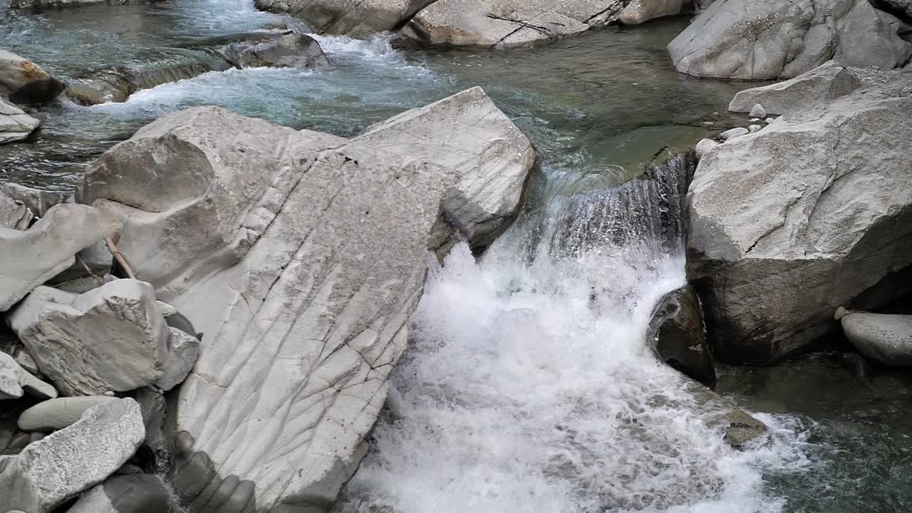 Clear blue water streaming true the rocks and falling down on a small waterfall in Lauterbrunnen Switserland. Close-up slowmo shot