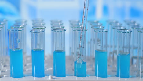 Lab-assistant-adding-green-liquid-in-test-tube-monitoring-chemical-reaction.-Technician-carefully-drips-the-solution-from-the-pipette-into-glass-tubes-for-DNA-analysis.-Pharmaceutics-Laboratory.-High-quality-4k-footage