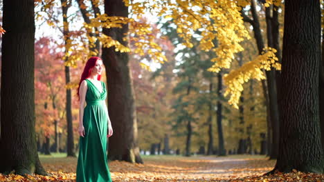 a woman in a green dress walks through an autumn park