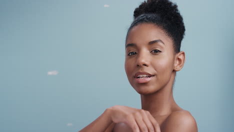 Zeitlupen-Schönheitsporträt-Einer-Schönen-Afroamerikanerin,-Die-Spielerisch-Federn-Bläst,-Die-Nackte-Haut-Berührt-Und-Sanfte-Hautpflege-Genießt-Und-Den-Körper-Auf-Blauem-Hintergrund-Sanft-Streichelt