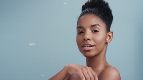 slow motion beauty portrait beautiful african american woman playfully blowing feathers falling touching bare skin enjoying soft skincare gently caressing body in blue background