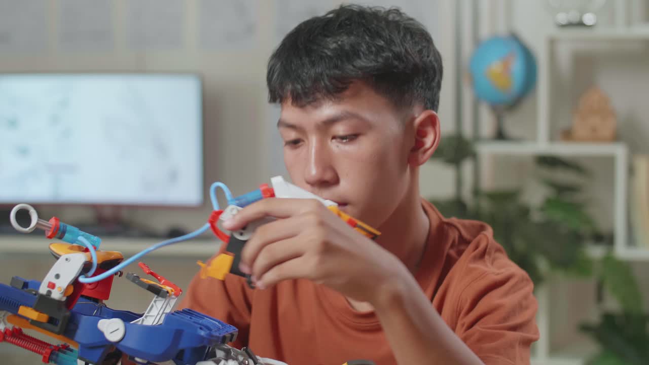 un niño asiático con una computadora portátil montando una mano de cyborg en casa.